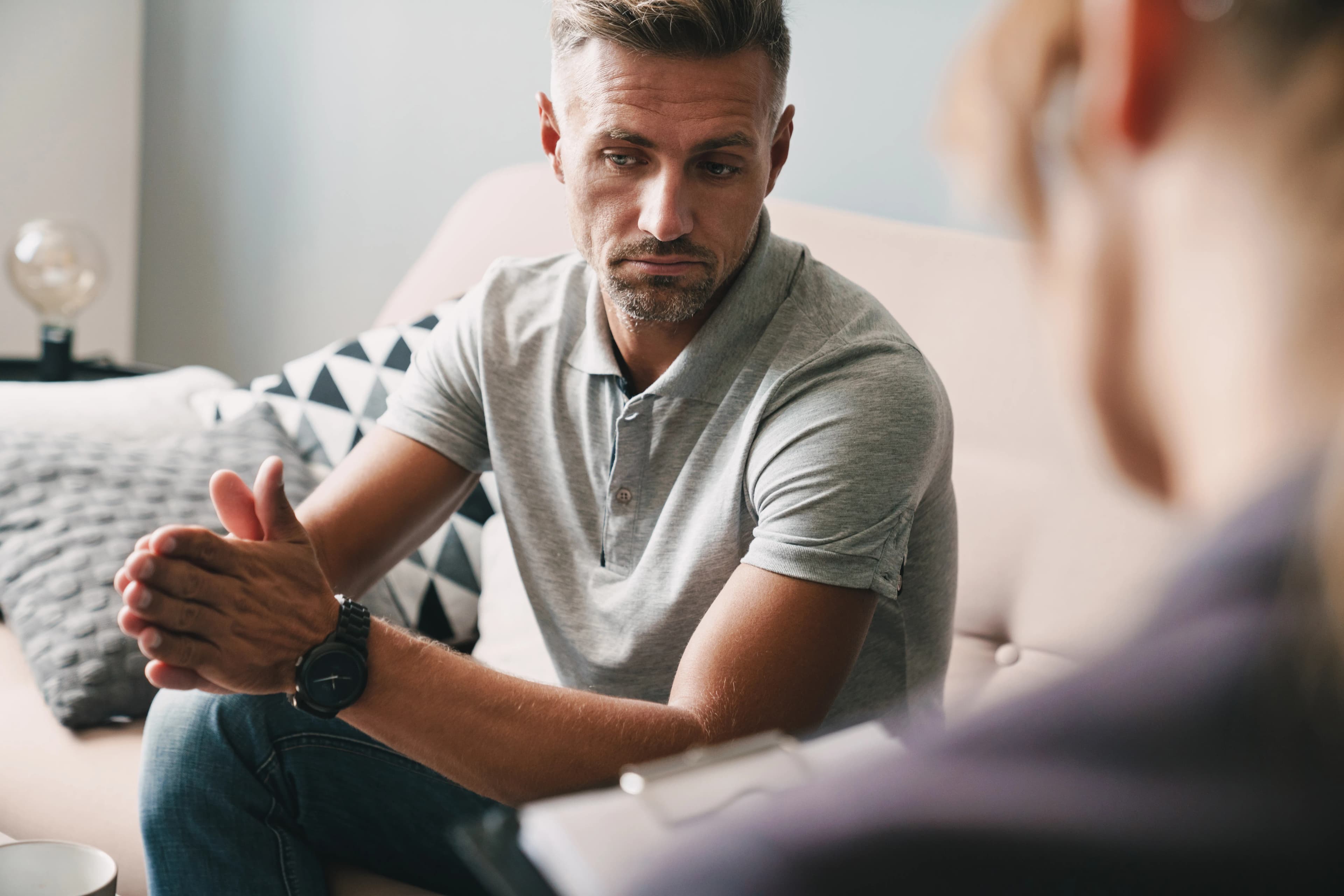 A man stood clasping his hands together whilst talking to a counsellor