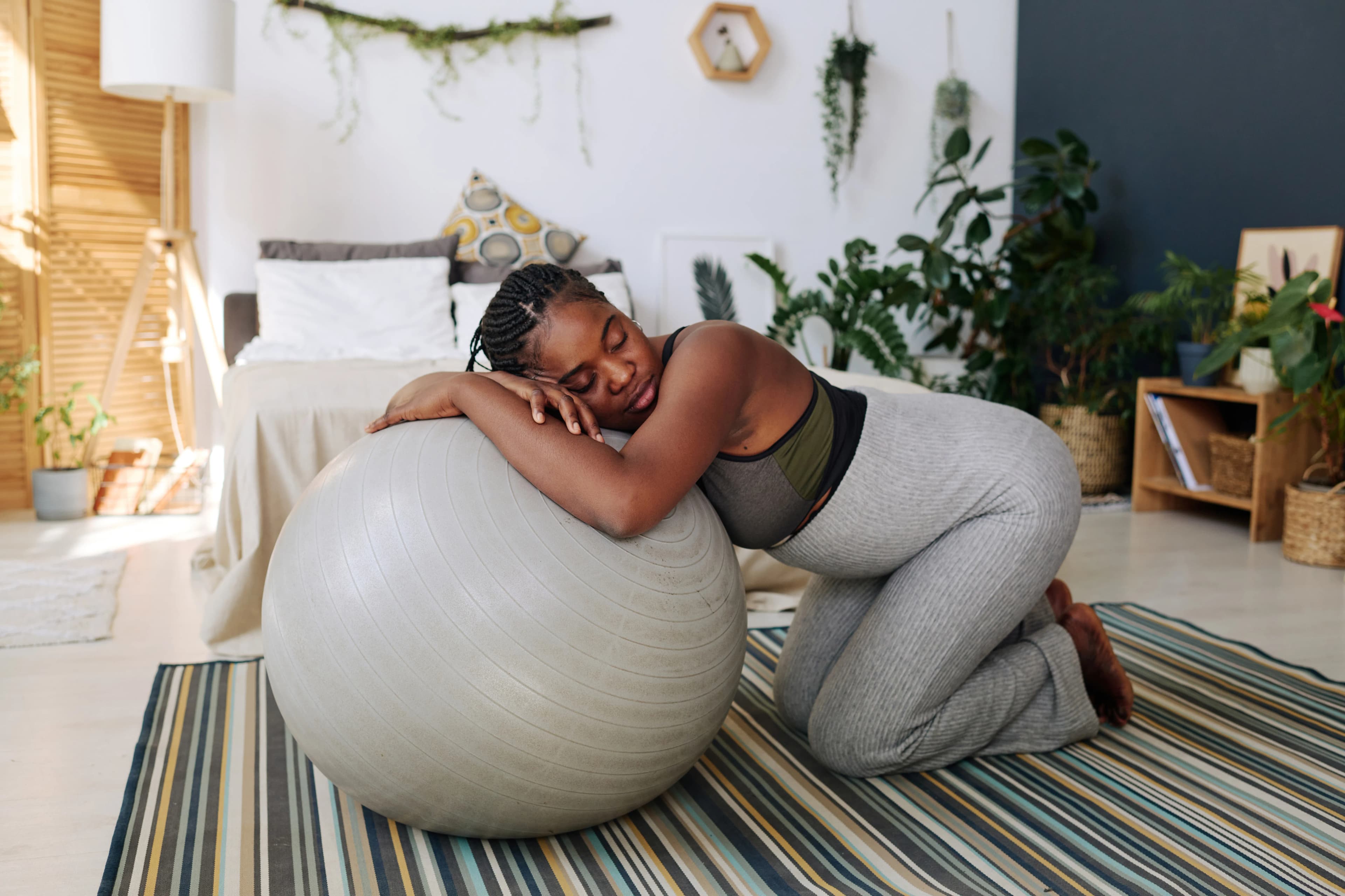A pregnant woman knelt on the floor leaning against an exercise ball
